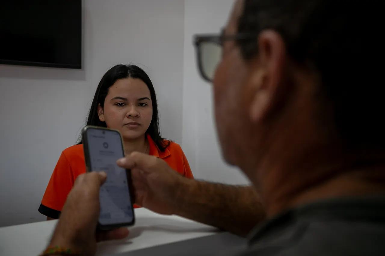 Atendente mostrando o aplicativo no celular para um caminhoneiro.